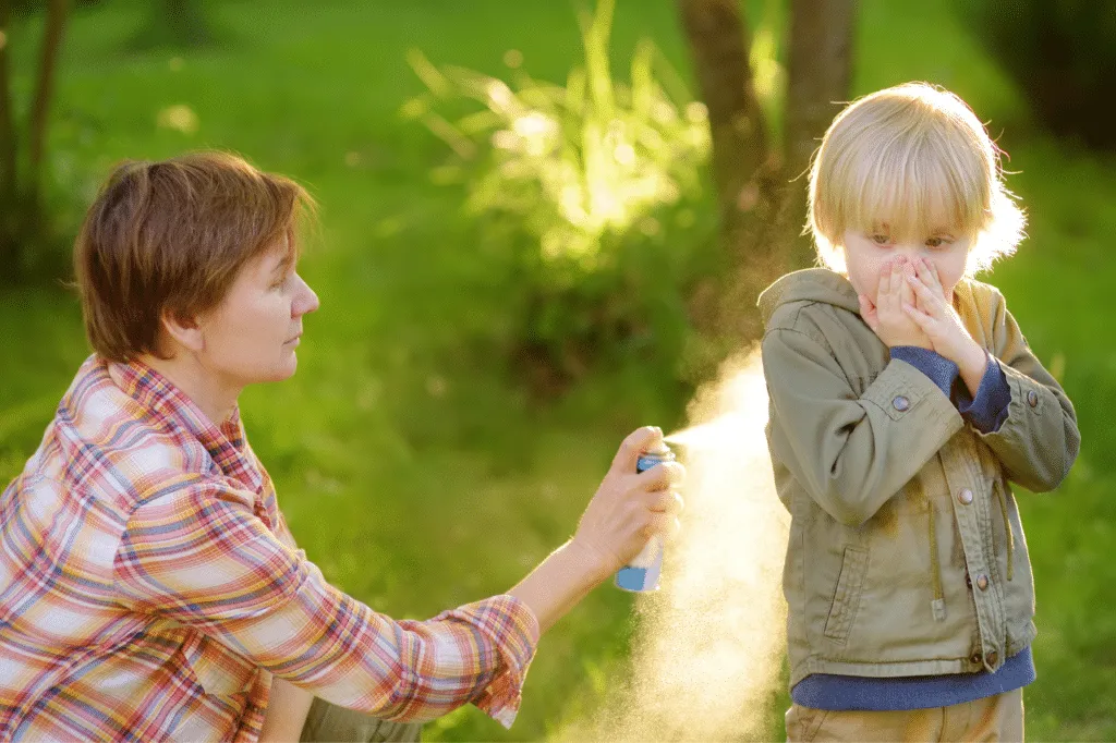 Una mamma che spruzza dello spray anti zanzara al suo bambino