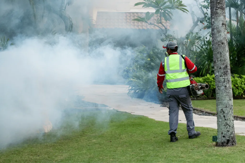 Disinfestatore che effettua una disinfestazione zanzare in un giardino con l'aiuto di un nebulizzatore
