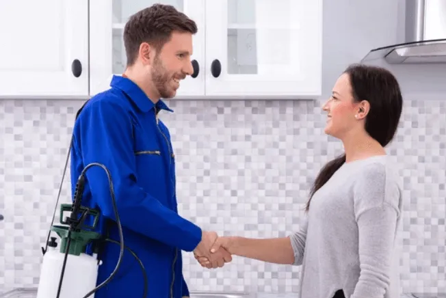 Una giovane donna mentre stringe la mano al disinfestatore
